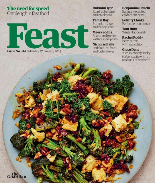 Overhead shot of a blue plate piled high with a vibrant salad featuring broccoli, tofu, and nuts, presented in a magazine spread.