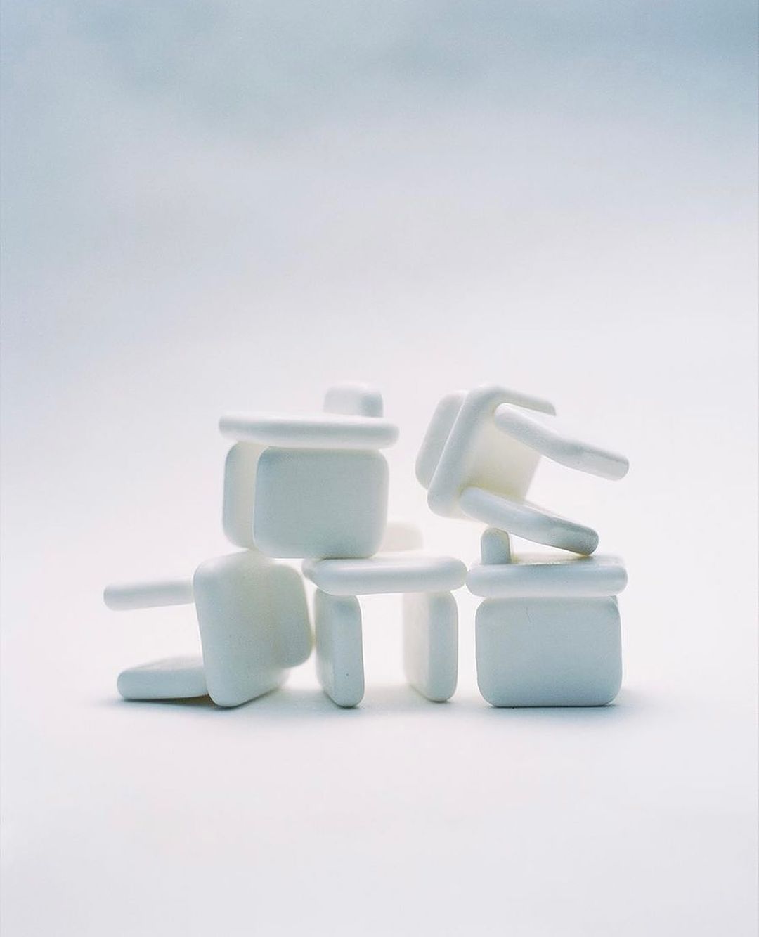 Stacked set of white table corner protectors creates an abstract composition on a white surface with an even, diffused light.