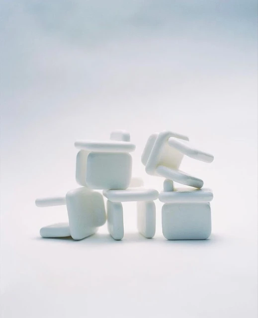 Stacked set of white table corner protectors creates an abstract composition on a white surface with an even, diffused light.
