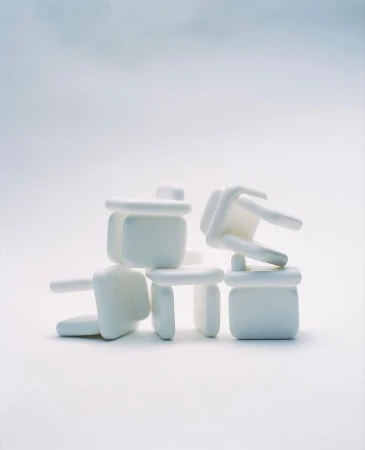 Stacked set of white table corner protectors creates an abstract composition on a white surface with an even, diffused light.