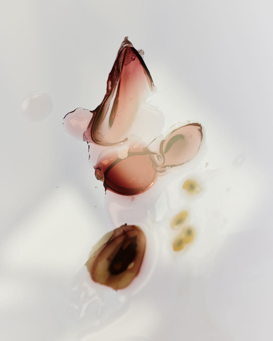 Macro shot of sliced figs showing pulp and seeds on a wet white surface with diffused lighting, highlighting the fruit's texture.