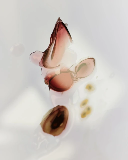 Macro shot of sliced figs showing pulp and seeds on a wet white surface with diffused lighting, highlighting the fruit's texture.