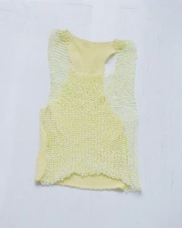 Textured pale yellow beaded tank top laid flat on a light white background