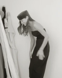 Candid portrait of a woman in a black strapless dress and pillbox hat laughing, photographed by Luba Kozorezova in Paris