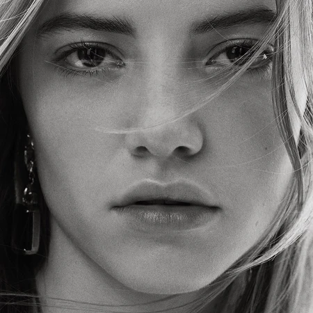 Close-up black and white portrait of a woman's face with strands of hair blowing across her eyes.