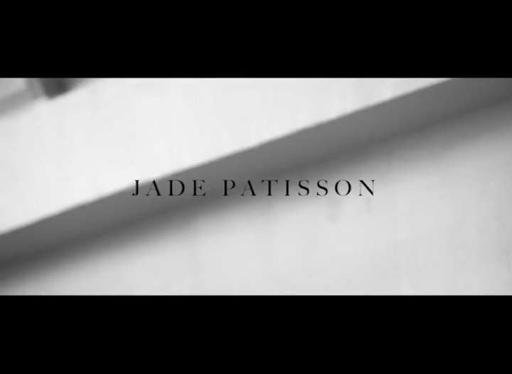 Monochromatic shot of a wall with subtle light and shadows, and bold, sans-serif text overlay with the name Jade Patisson.