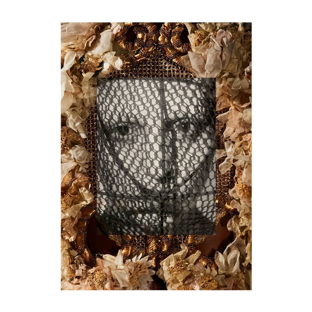 Close-up portrait of a person framed with gilded materials and fabric flowers, with a black lace covering the face.