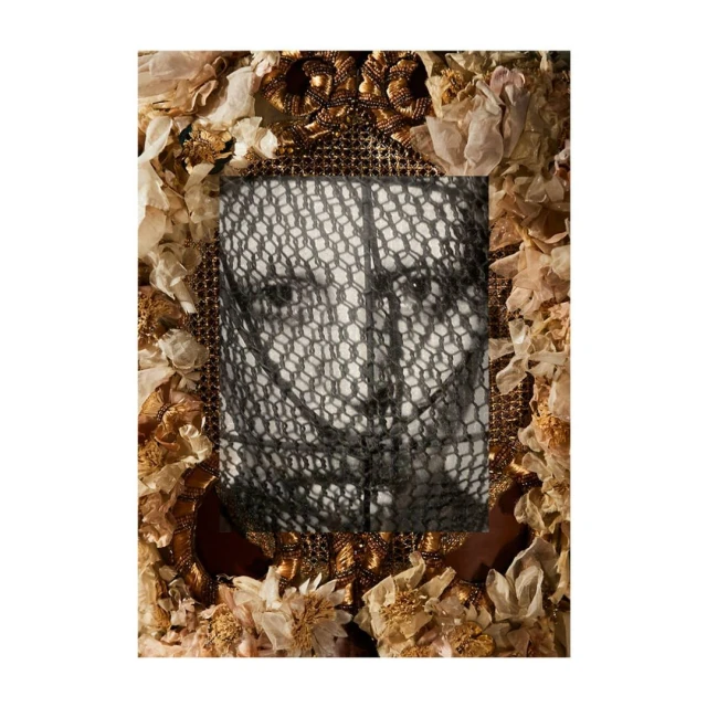 Close-up portrait of a person framed with gilded materials and fabric flowers, with a black lace covering the face.