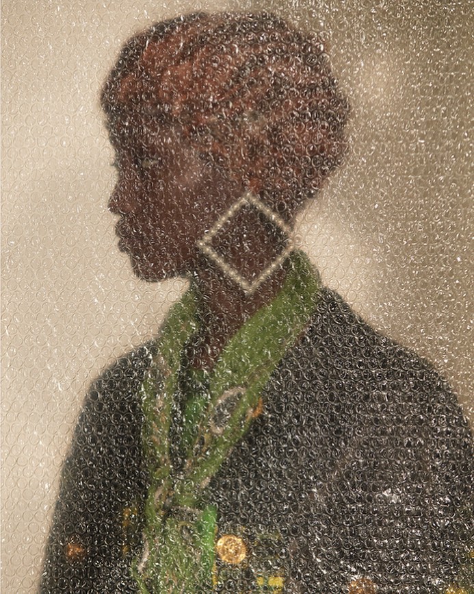 Portrait of an African American woman with short brown hair wearing a black and green jacket with a bubble wrap overlay.