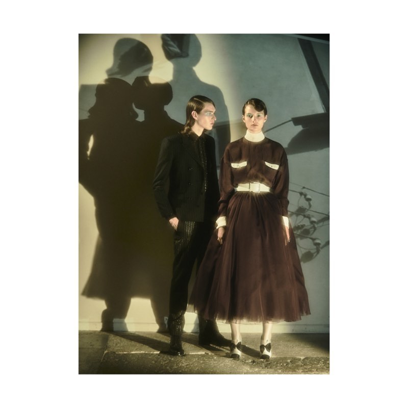 Two models standing against a wall with prominent shadows cast behind them in a photographic portrait by Lucian Bor.
