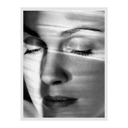 Monochrome close-up portrait of a woman with closed eyes and horizontal light patterns across her face.