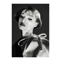 Monochrome portrait of a woman with styled hair and false eyelashes wearing a structured bow top by photographer Lucian Bor.