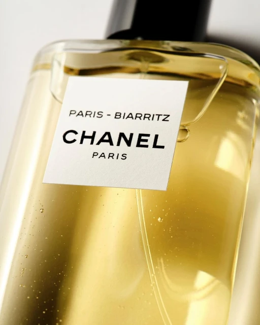 Close-up of Chanel Paris-Biarritz fragrance in a clear glass bottle with a black cap and a white label with black text.
