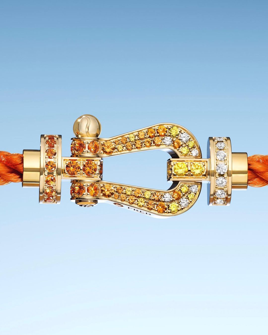 Close-up of a gold clasp bracelet with embedded diamonds, set against a light blue gradient background, showcasing jewelry design.