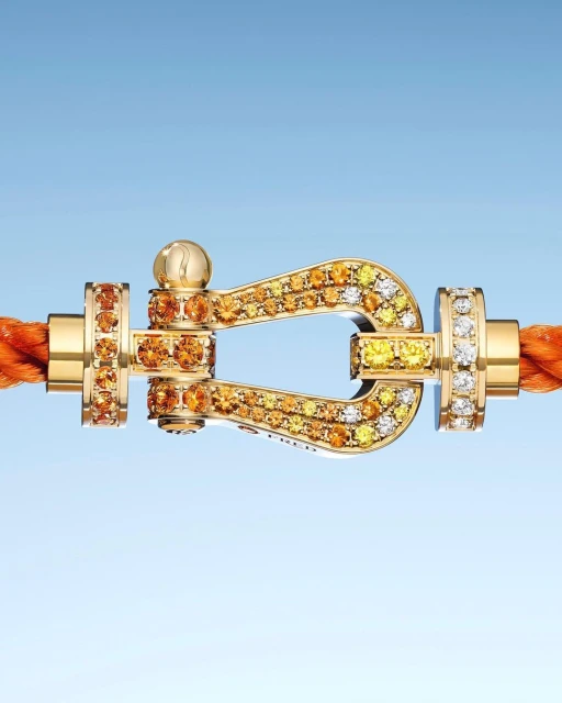Close-up of a gold clasp bracelet with embedded diamonds, set against a light blue gradient background, showcasing jewelry design.