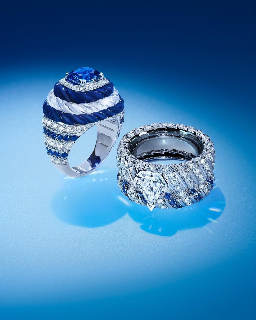 Close-up of two silver rings with blue and white stones displayed on a blue gradient background, jewelry and luxury concept.