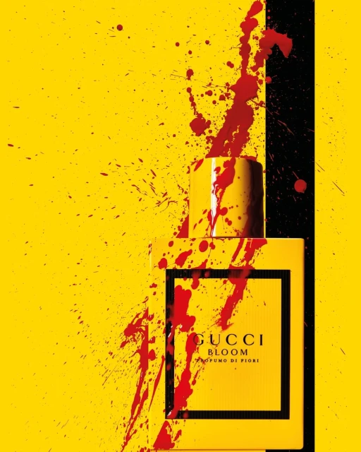 Gucci Bloom perfume bottle against a vivid yellow background with black stripe and splatters of red liquid for a beauty advertisement.