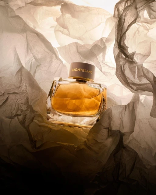 Montblanc perfume bottle on a crumpled tissue paper background, showcasing its amber liquid and elegant design in a studio setting.