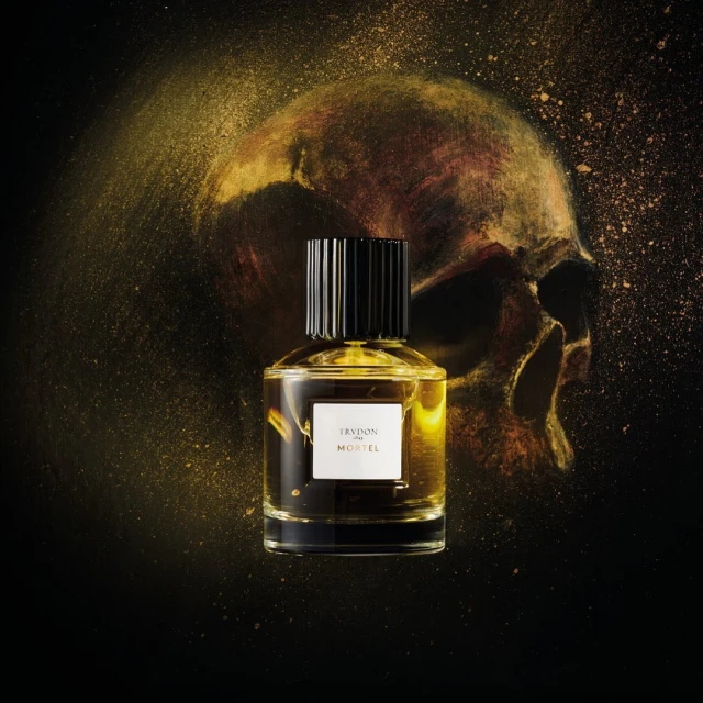 Still life shot of a black and gold perfume bottle with a skull graphic background and gold dust for Beauty and Fashion marketing.