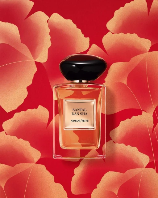 Elegant Giorgio Armani 'Santal Dan Sha' perfume bottle with black cap on a vibrant red background with abstract floral pattern.