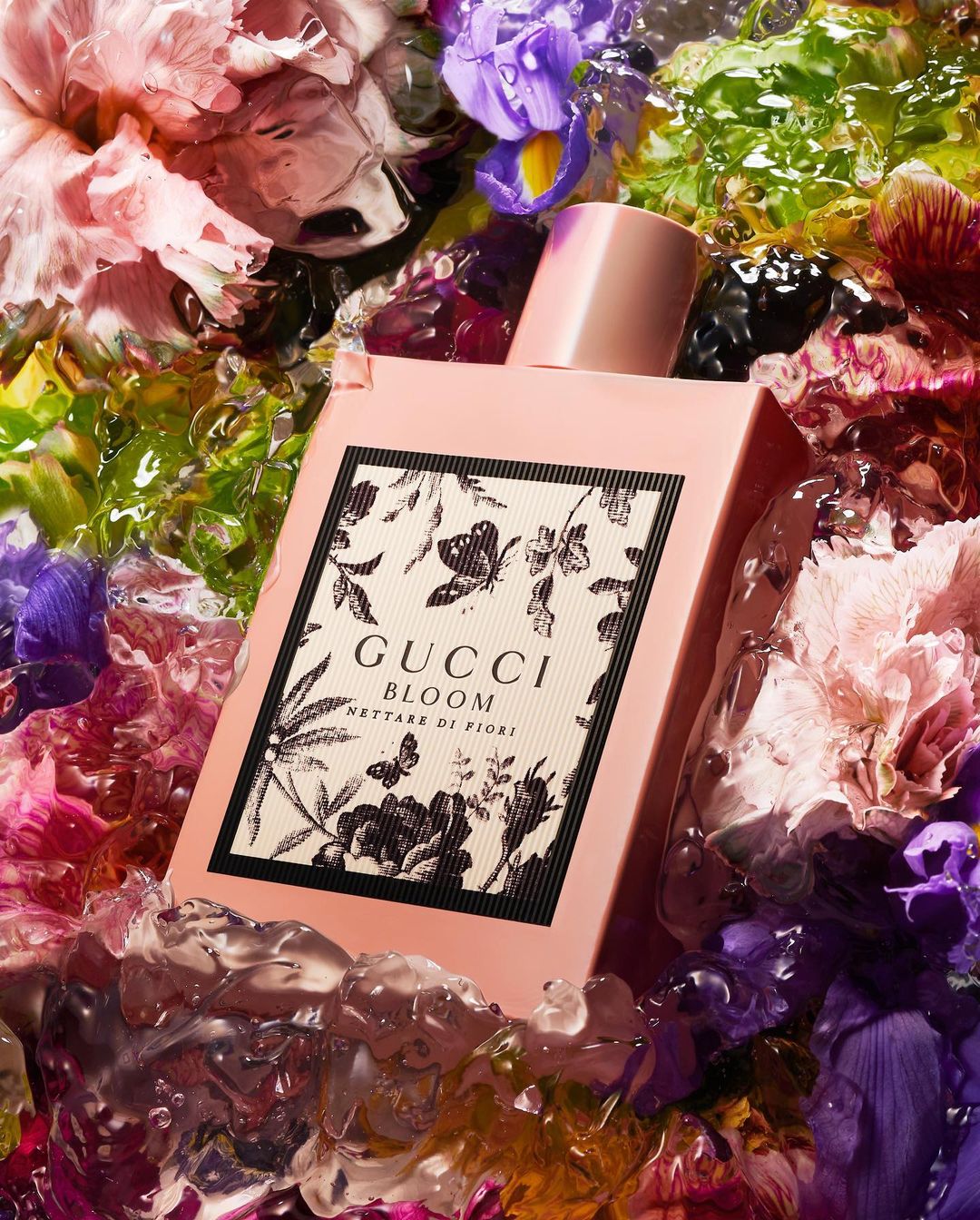 Gucci Bloom Nettare di Fiori perfume bottle surrounded by colorful flowers and ice. Beauty shot for product advertising.