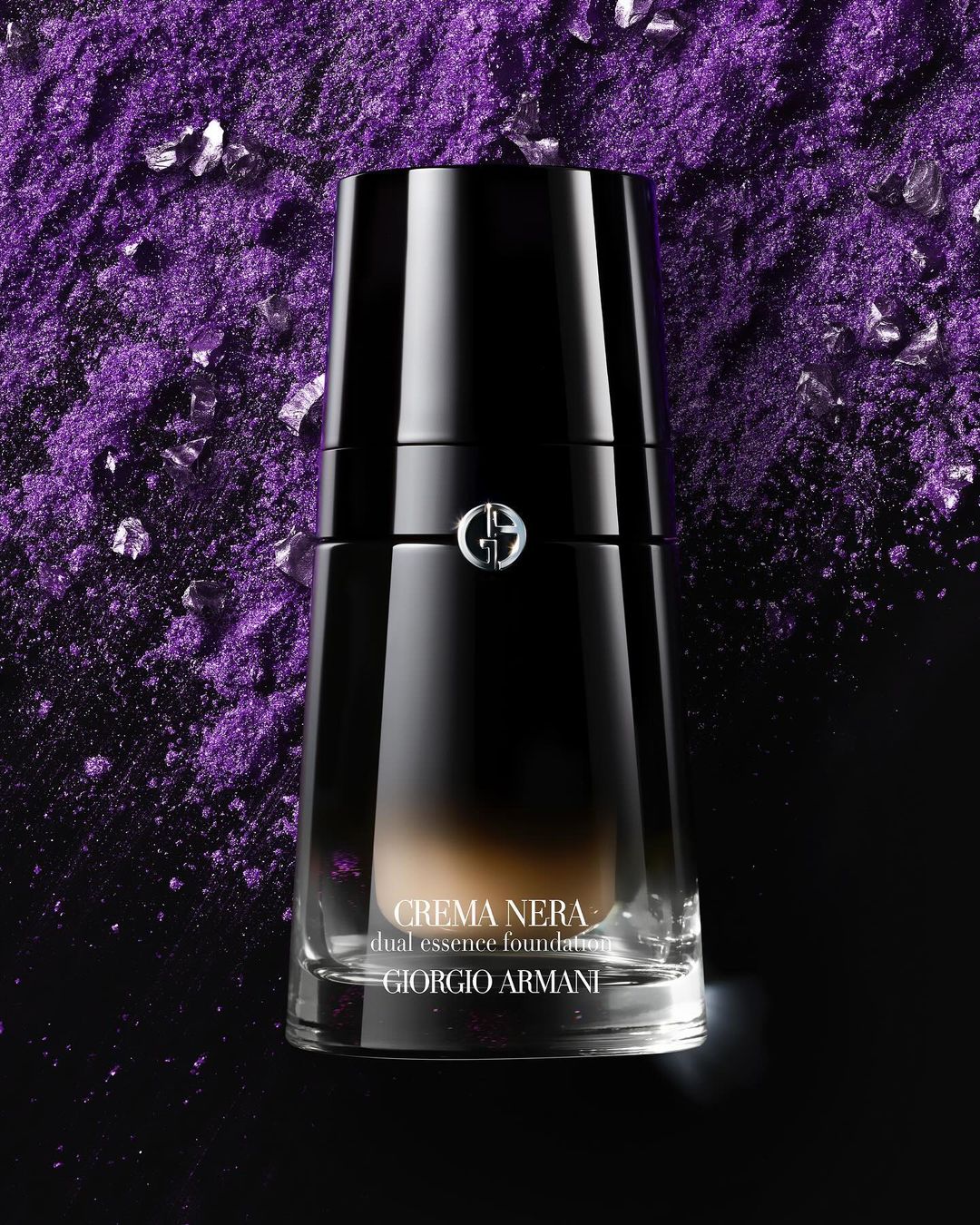 Close-up of black Crema Nera dual essence foundation by Giorgio Armani with purple granular background.