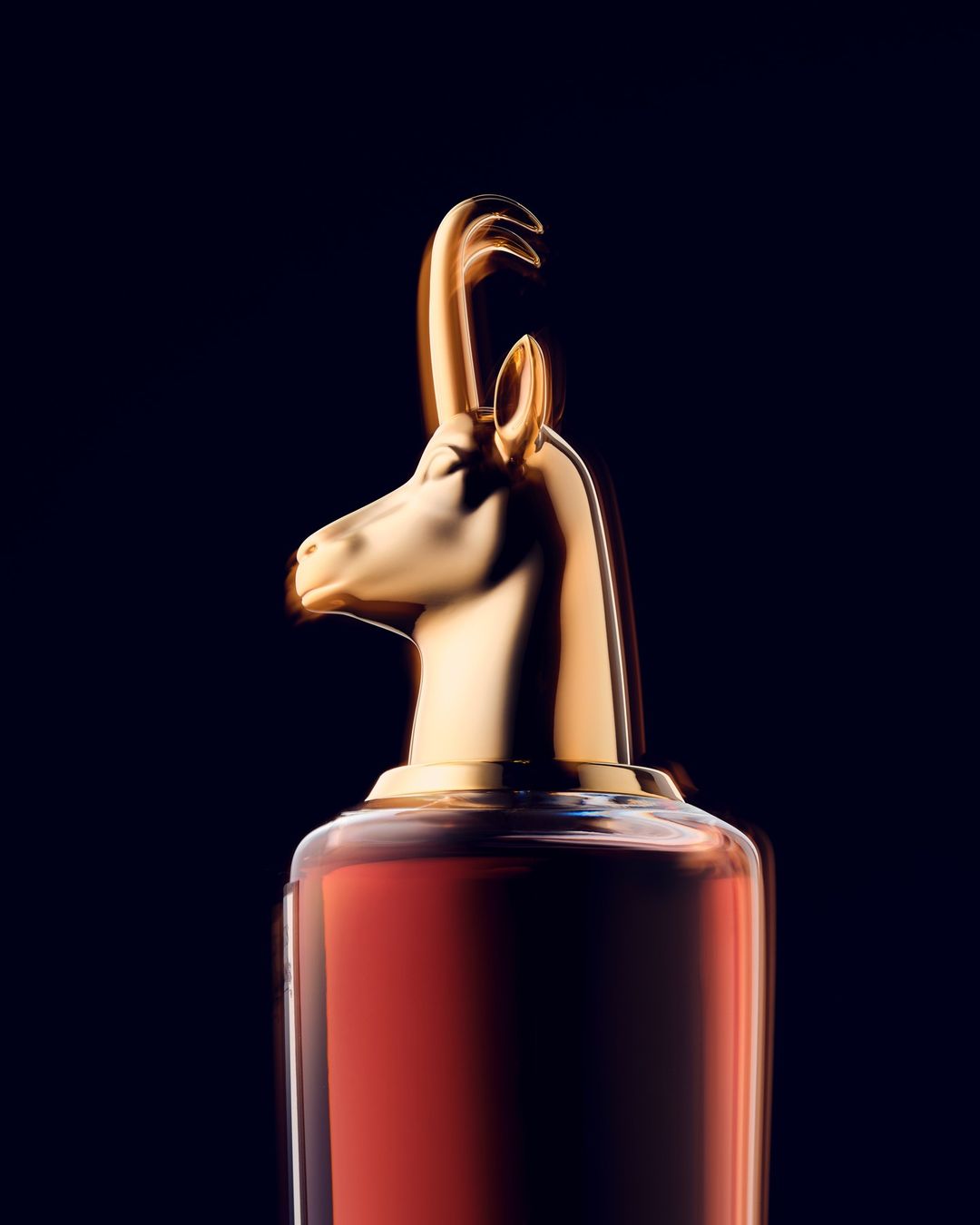 Elegant presentation of a perfume bottle with a golden animal-shaped cap against a dark backdrop, creating a luxurious aesthetic.
