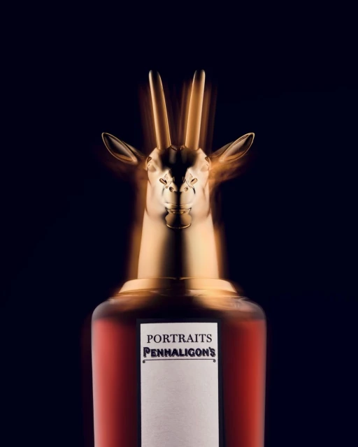 A bottle of Penhaligon's Portraits perfume with a gold antelope head stopper against a dark background, beauty and luxury concept.