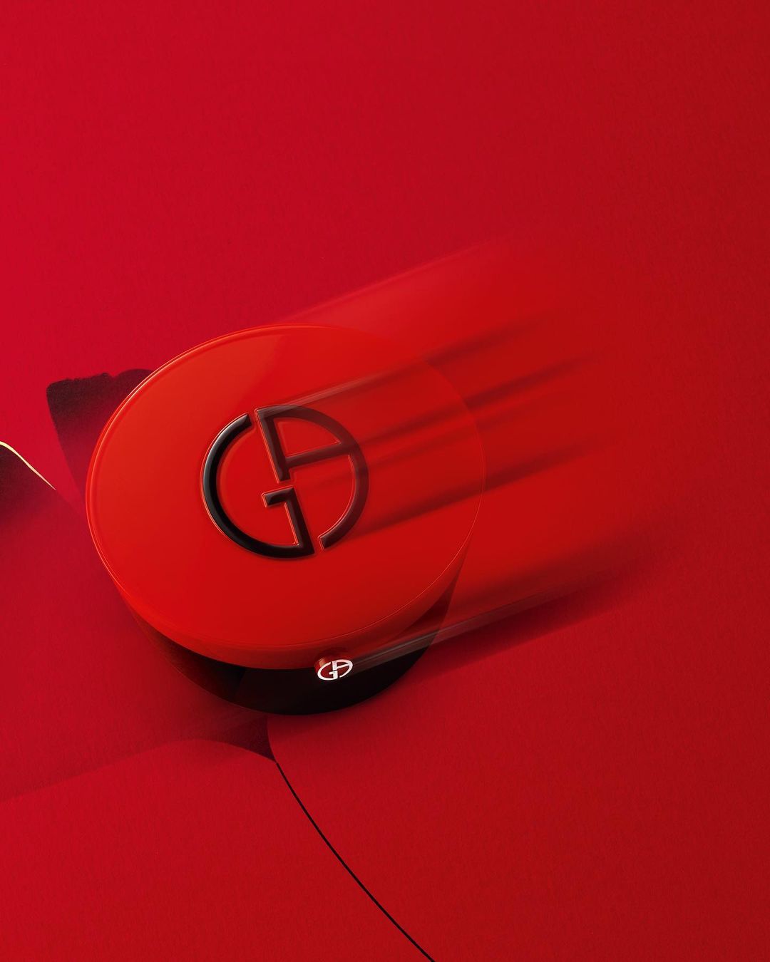 Vibrant still life showcases a red Giorgio Armani beauty compact with the iconic GA logo, set against a matching red backdrop.