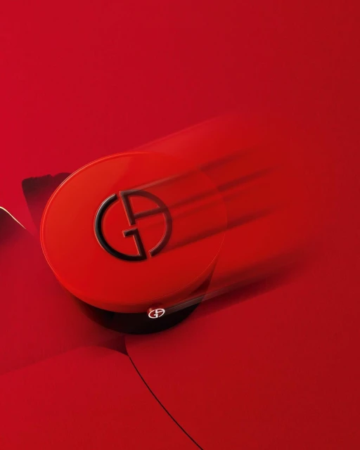 Vibrant still life showcases a red Giorgio Armani beauty compact with the iconic GA logo, set against a matching red backdrop.
