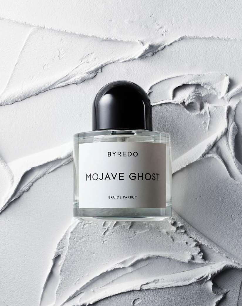 Close-up of a Byredo Mojave Ghost perfume bottle with a black cap against a white textured background. Beauty, fragrance, product shot.