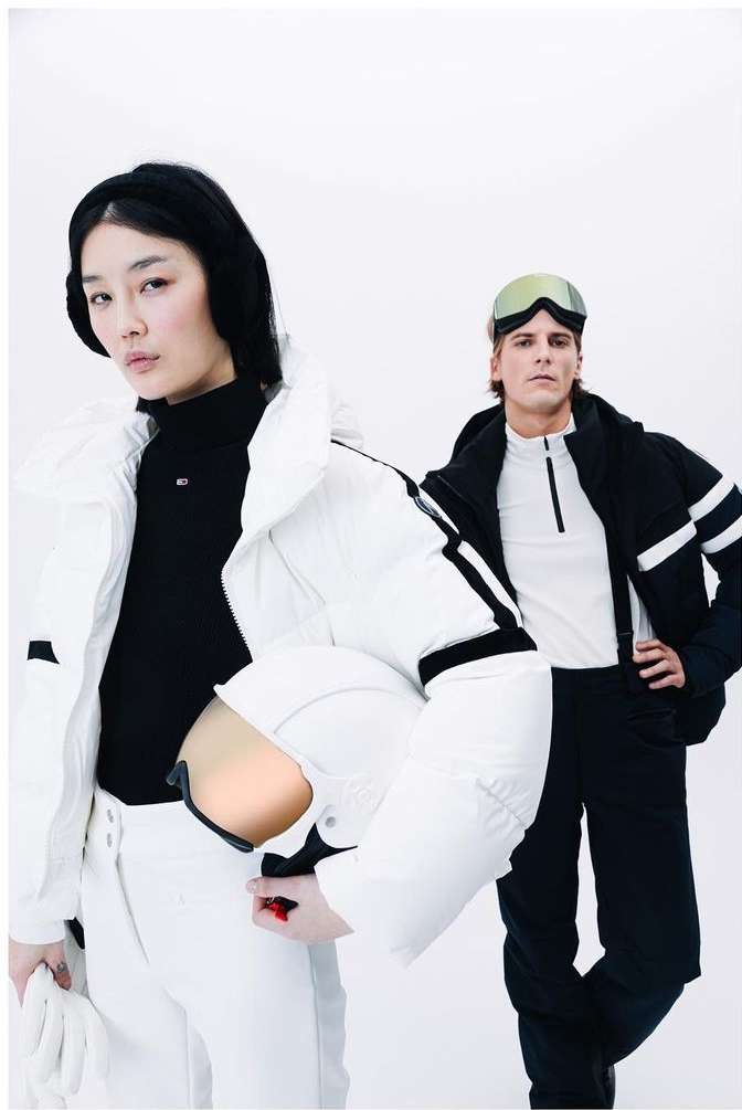 Two fashion models pose against a bright white backdrop, showcasing winter ski attire and accessories, including jackets, goggles, and gloves.