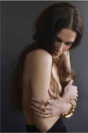 Portrait of a woman with long brown hair wearing gold jewellery and rings photographed by Lucie Sassiat in Paris