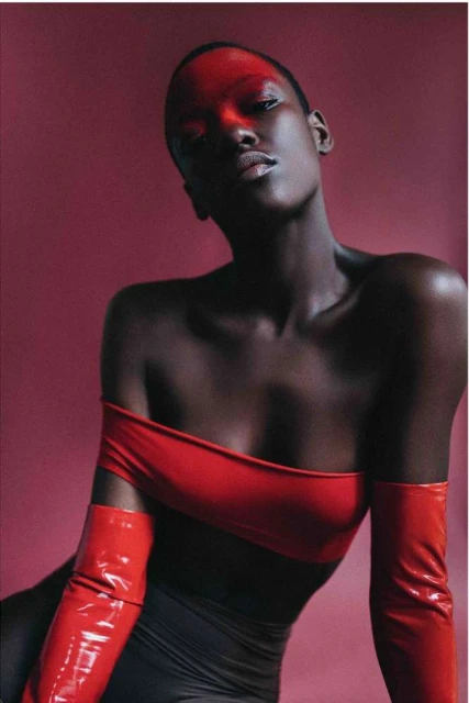 Striking studio portrait of a Black woman in red gloves and top against a red background, showcasing fashion and beauty elements.