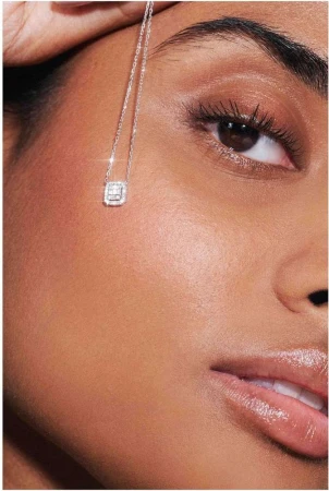 Extreme close-up beauty portrait of a woman wearing a delicate silver diamond pendant necklace against her cheek, photographed by Lucie Sassiat