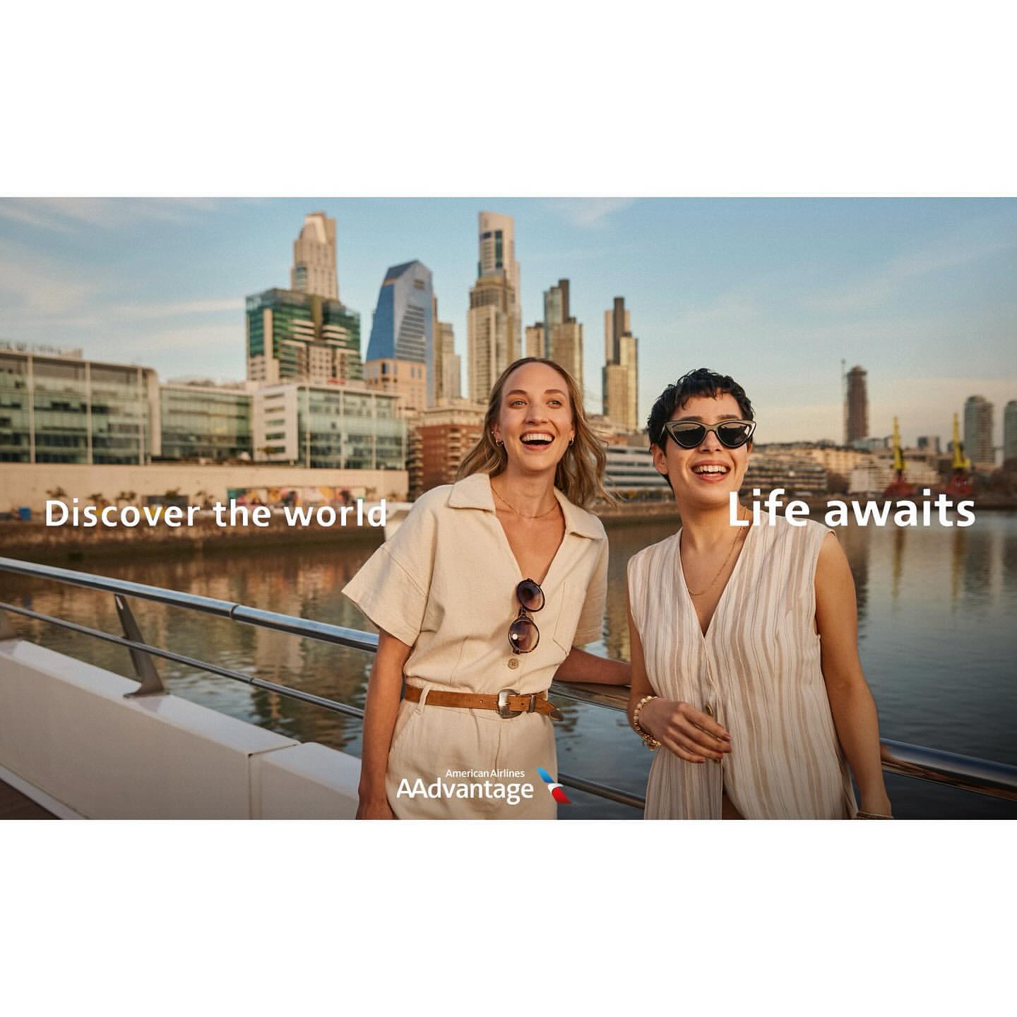 Two women smile in an American Airlines AAdvantage ad. They are on a boat with a cityscape of Buenos Aires in the background.