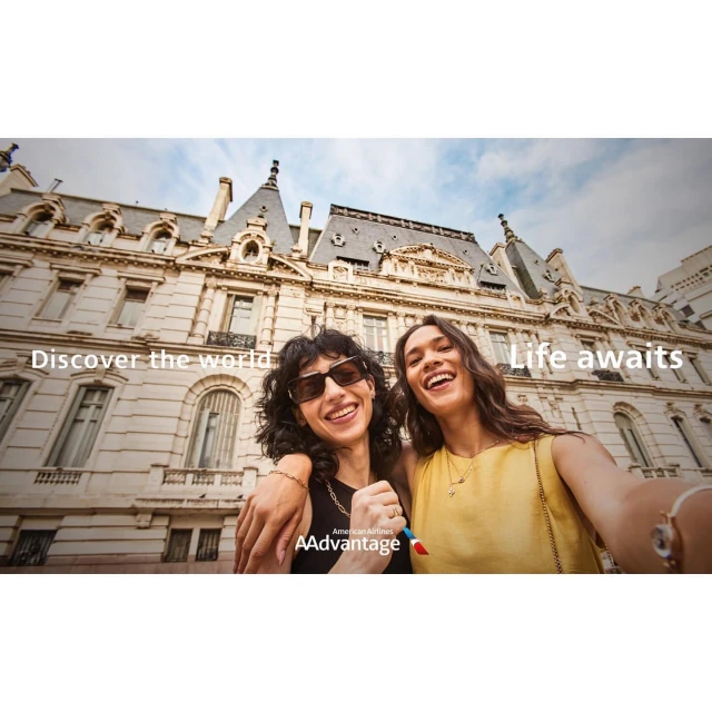 Two smiling women pose in front of a building, with text overlay 'Discover the world' and 'Life awaits' and an airline logo visible.