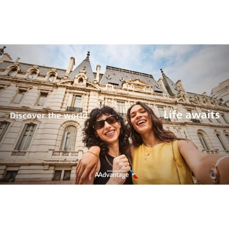 Two smiling women pose in front of a building, with text overlay 'Discover the world' and 'Life awaits' and an airline logo visible.