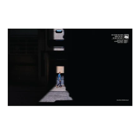 A man walking through a narrow shaft of light in a dark brutalist architectural corridor by Lucila Blumencweig.