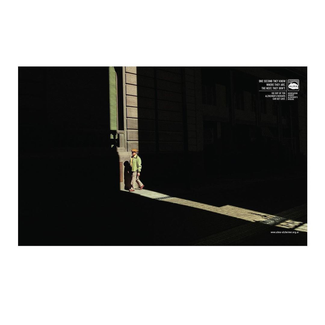 Young boy walks in a beam of light on a dark city street, creating strong contrast and shadows on the surrounding buildings.