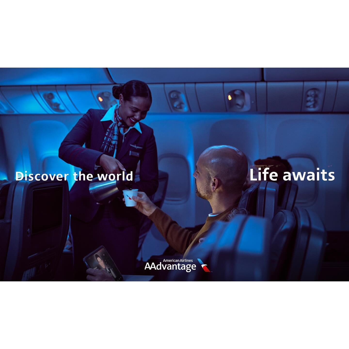 Flight attendant serves coffee to a passenger on an airplane in blue lighting with brand logos of American Airlines AAdvantage.