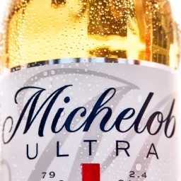 Close-up macro shot of a chilled Michelob Ultra bottle covered in water droplets with golden liquid inside.