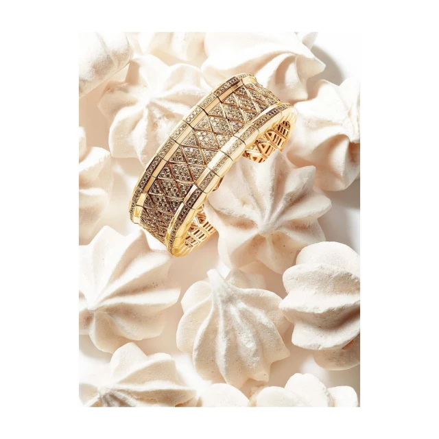 Elegant gold diamond bracelet on a bed of meringue cookies, showcasing jewelry design and food styling in a soft, inviting composition.