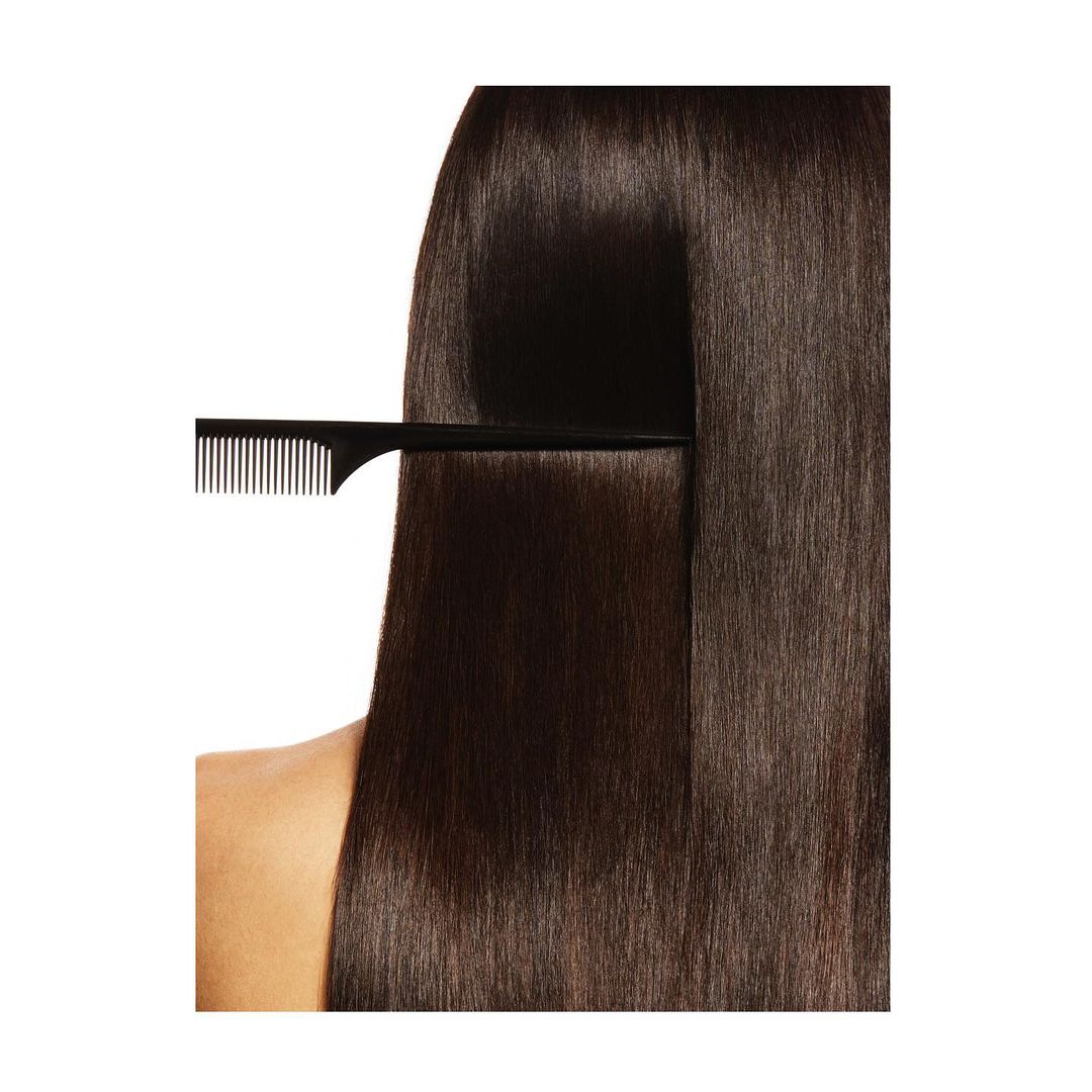 Close-up of long, straight brunette hair being combed with a black comb against a clean white background in a beauty context.
