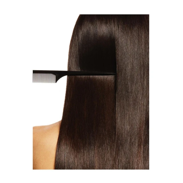 Close-up of long, straight brunette hair being combed with a black comb against a clean white background in a beauty context.