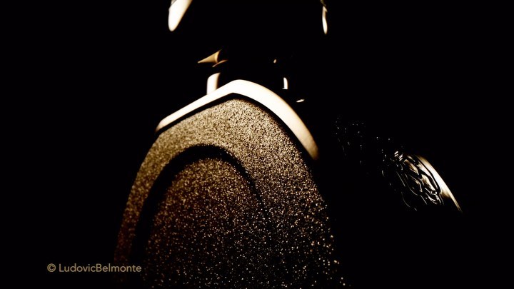 Close-up shot of a microphone with a textured surface and a silver emblem against a stark black background. Studio equipment.