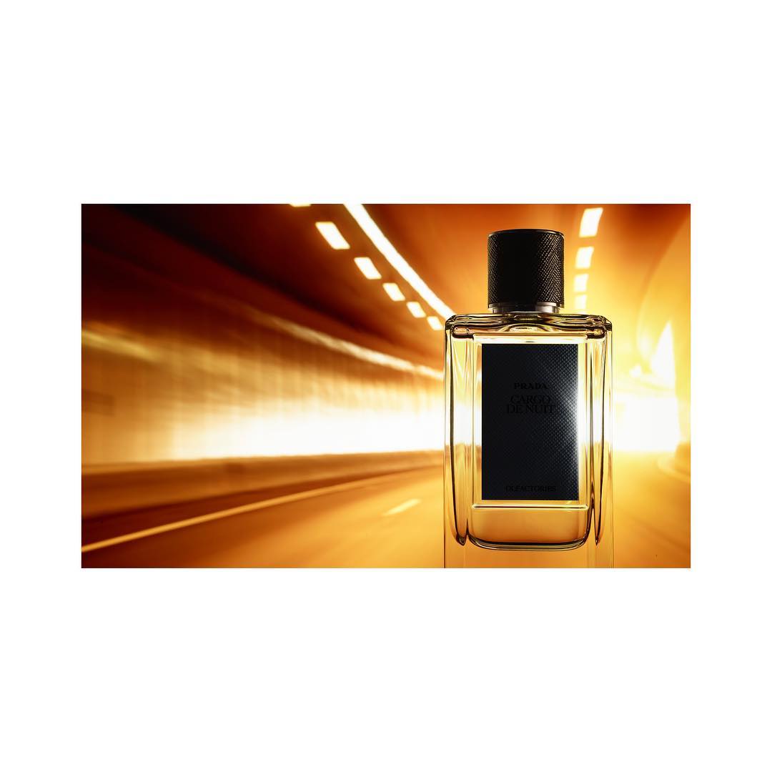 Prada Ocean Luna Rossa fragrance stands against a blurred background showing an abstract tunnel of lights on a wet highway.