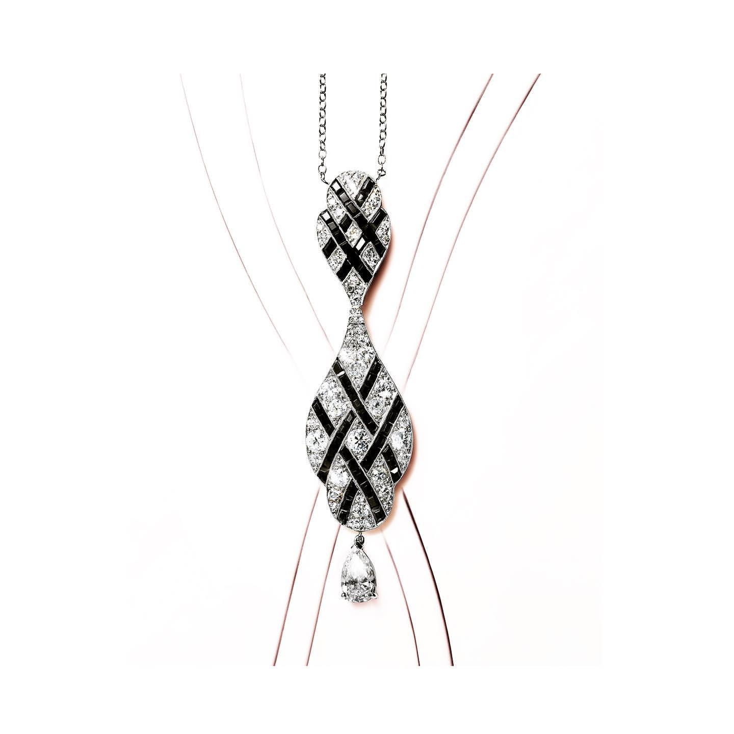 Elegant necklace with a woven pattern of black and clear gemstones on a delicate silver chain, displayed against a simple background.