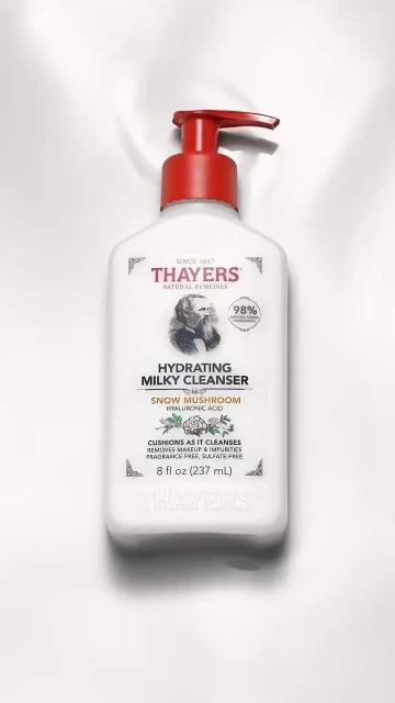 White bottle of Thayers Hydrating Milky Cleanser with red pump on white backdrop. Skincare product shot for beauty and personal care.