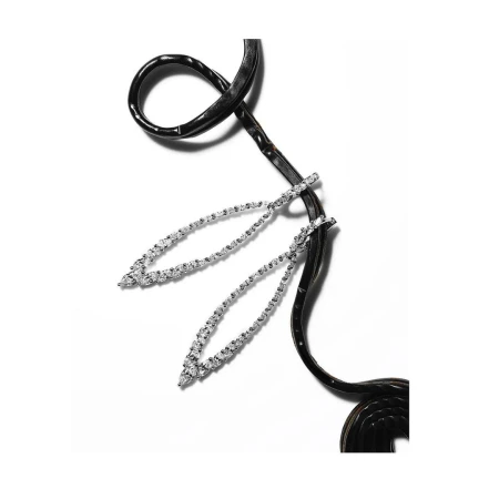Elegant jewelry flat lay: two silver drop earrings featuring diamond stones, displayed with a black leather cord on white background.
